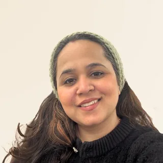 anshuli, founder of openthings, smiling, in a black sweater and a green knitted headband